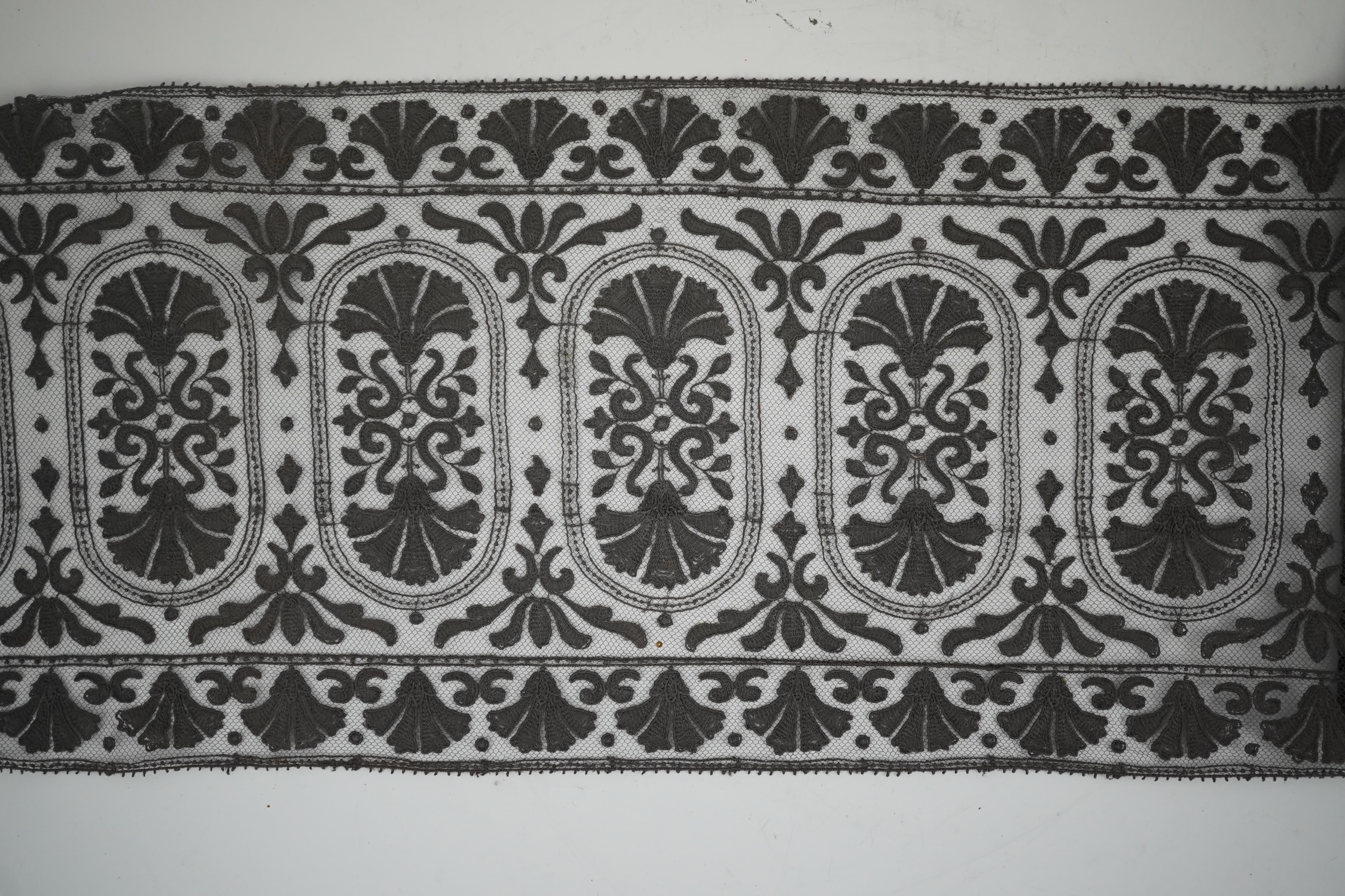 An unusual 19th century decorative length of charcoal grey machine furnishing lace, attributed to Christopher Dresser, together with a similar grey lace bonnet veil, both possibly Nottingham lace, furnishing lace 300cm j